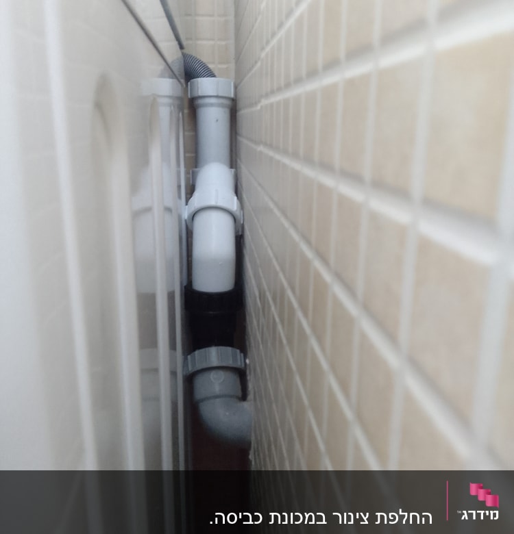 צינור פלסטיק לבן עם מחברים ליד קיר אריחים